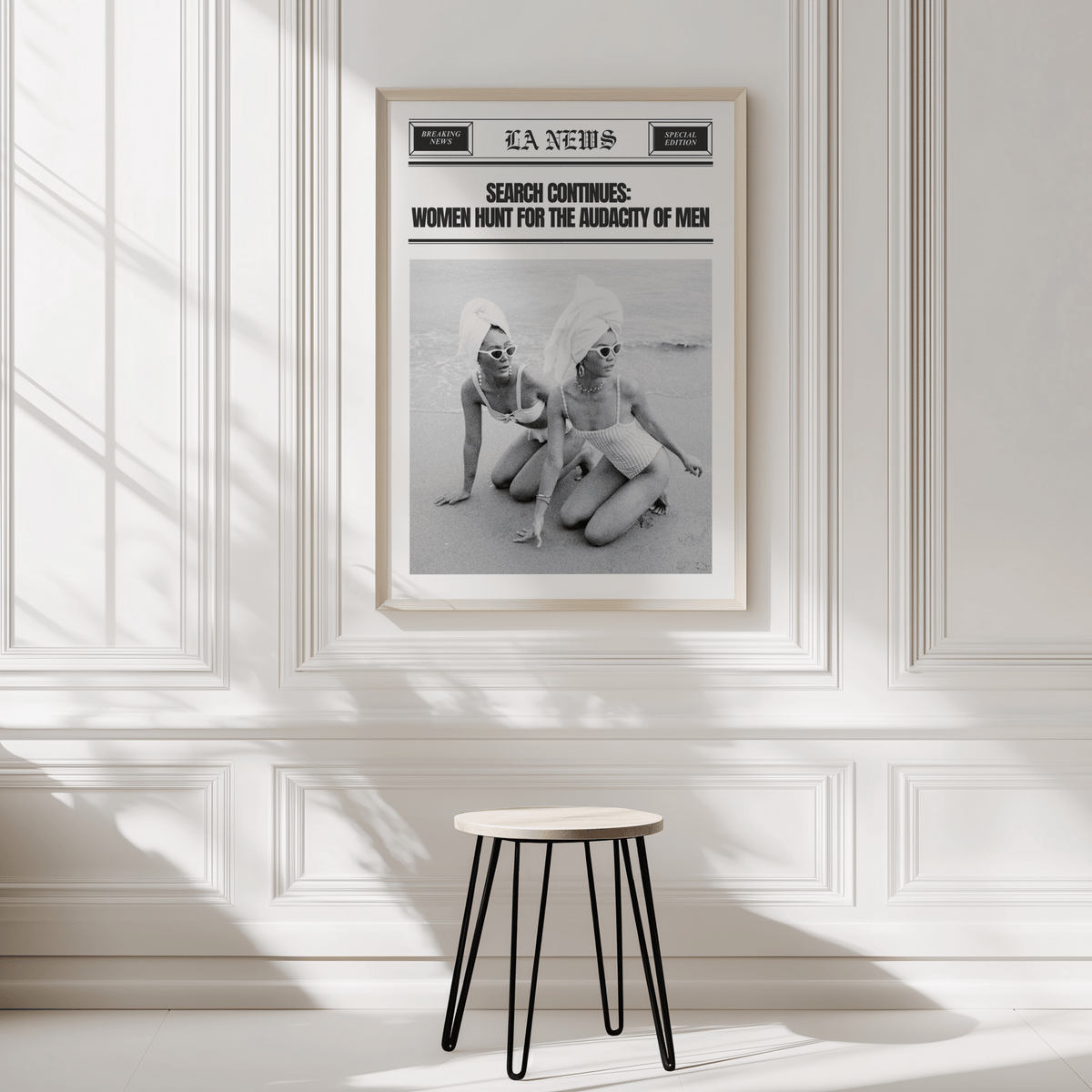 Vintage newspaper print in a natural frame on a white panelled wall above a black stool
