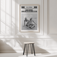 Vintage newspaper print in a natural frame on a white panelled wall above a black stool