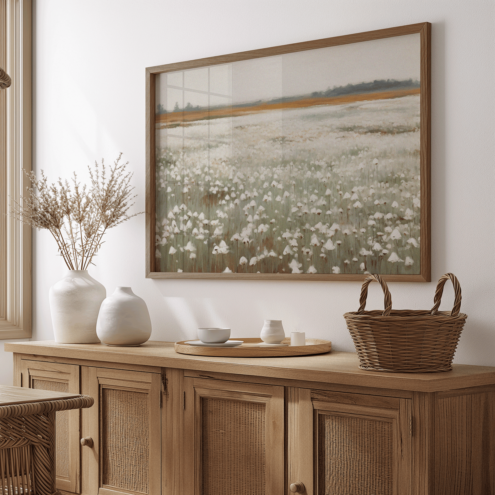 muted wildflower field wall art framed in natural wood, vintage landscape artwork for neutral dining room decor above a wooden side table with vintage vases, dried flowers and wicker basket