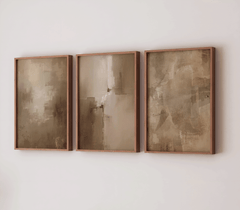 Set of three large warm beige and moody, earthy abstract canvas wall art prints in brown wood frames on a white wall