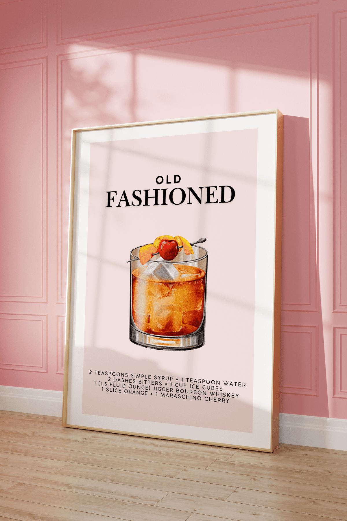 Whiskey cocktail print in a natural frame leaning against a pink panelled wall