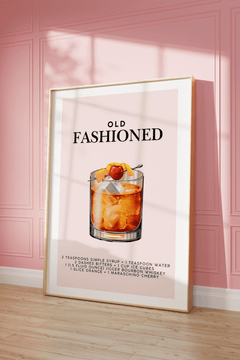 Whiskey cocktail print in a natural frame leaning against a pink panelled wall