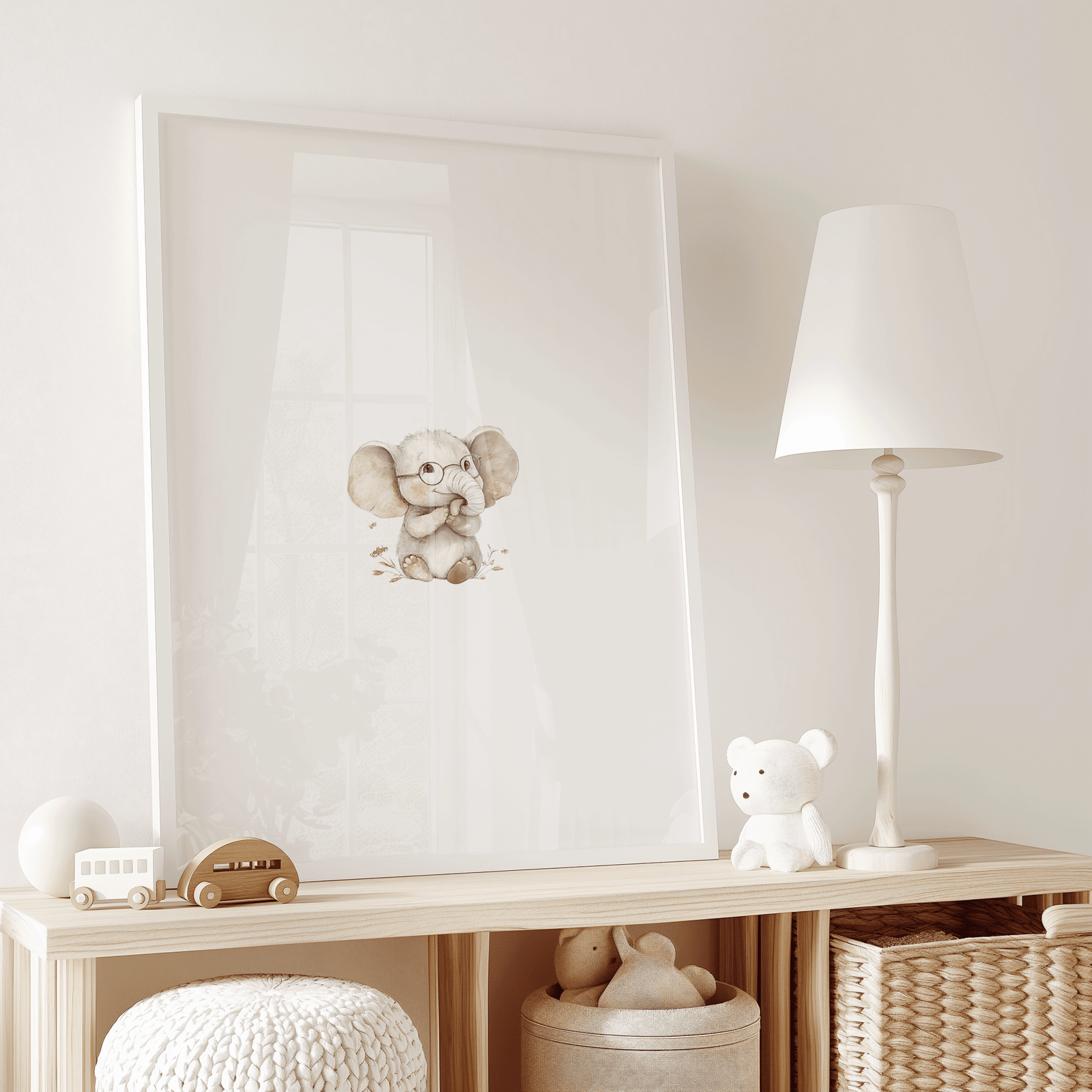 Neutral elephant nursery art print framed in white wood, styled on wooden shelf in a minimal, boho play room beside white lamp and plush toy.