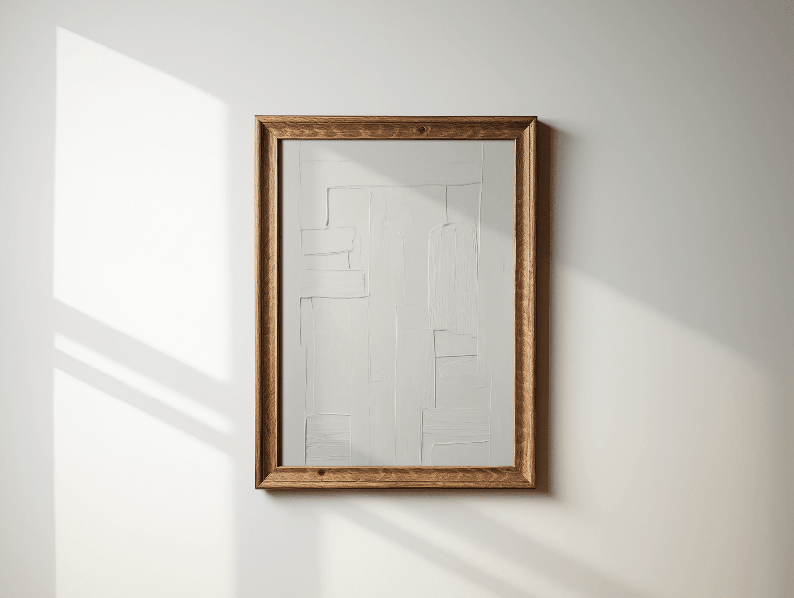 Wooden-framed all-white faux-textured minimal abstract wall art print on a white wall with sunlight casting shadows.