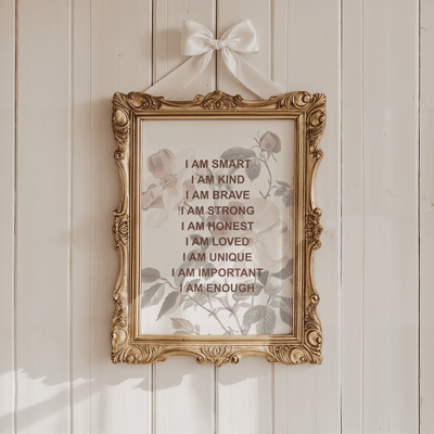 Wildflower affirmations print in an ornate gold frame hung with a white ribbon bow on a cream panelled wall