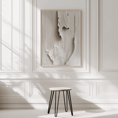 Paint-like faux-textured beige and white minimal abstract art framed on a white wall with a small stool in front.