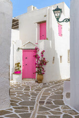 Traditional Cycladitic alley with narrow street, whitewashed houses and a blooming bougainvillea in Marpissa Paros island, Greece.
